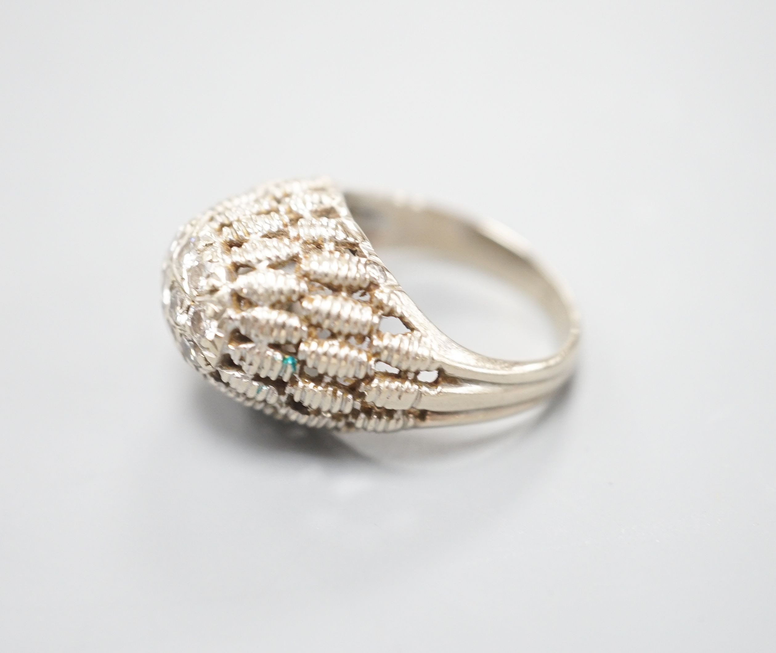 A continental textured white metal and diamond cluster set domed top dress ring, size K/L, gross weight 5.5 grams.